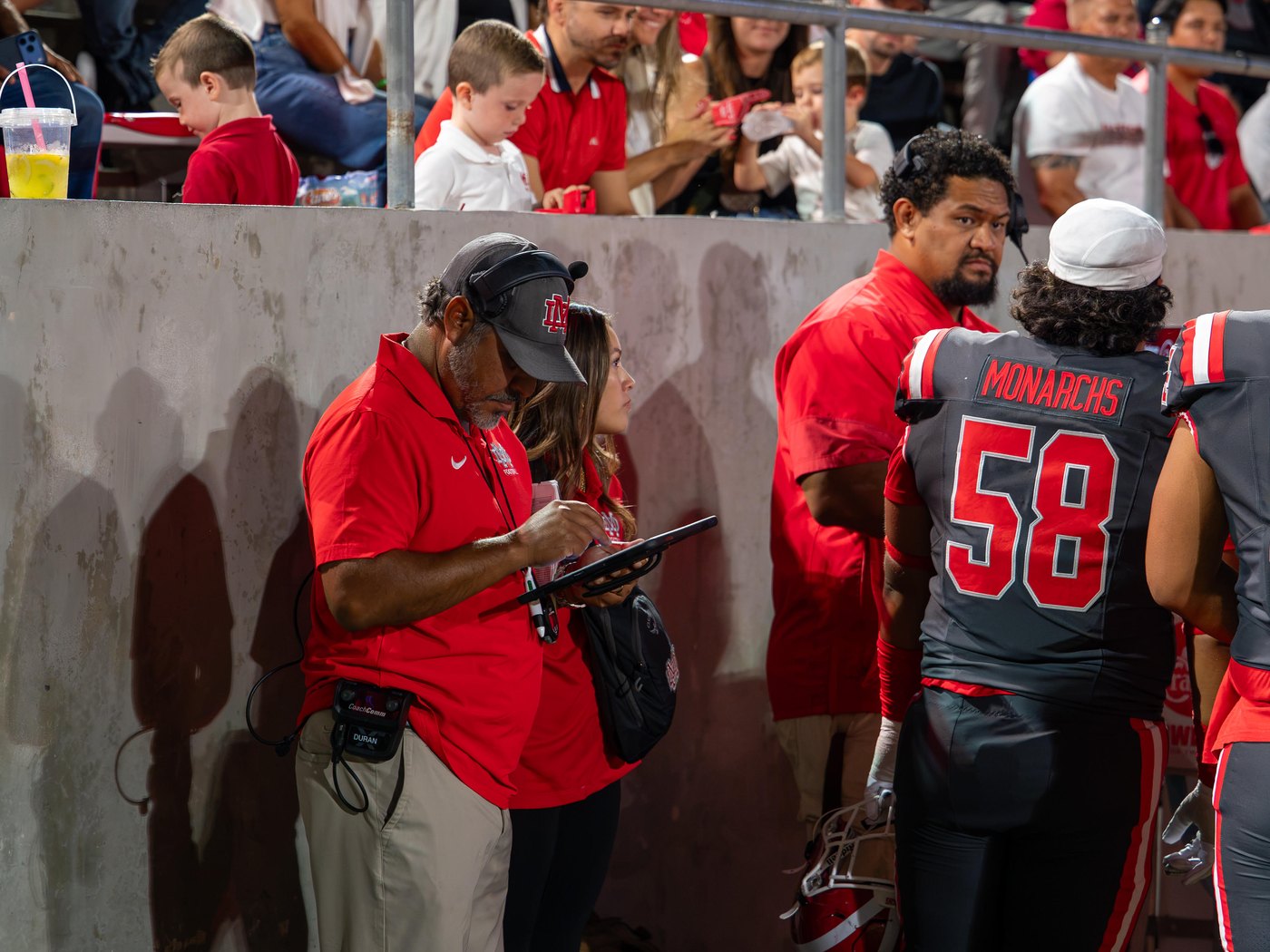 Mater Dei football staff reviewing SkyCoach replay on a sideline tablet during a game